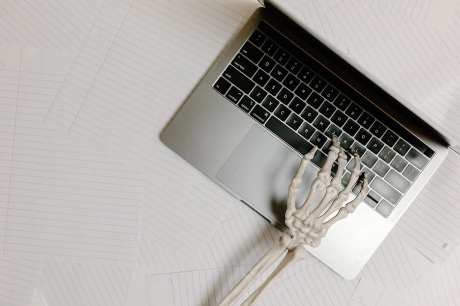 Osoba soustředěně píšící poznámky do zápisníku u pracovního stolu.